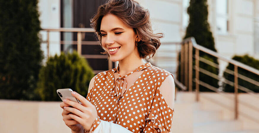 lady with clear skin checking her phone while walking outside