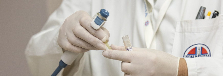 Healthcare professional using a pipette and test tube for a laboratory experiment